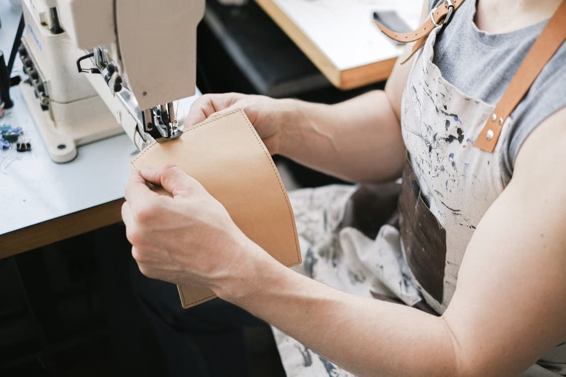 Ein Lederteil wird von Hand an der Nähmaschine geführt